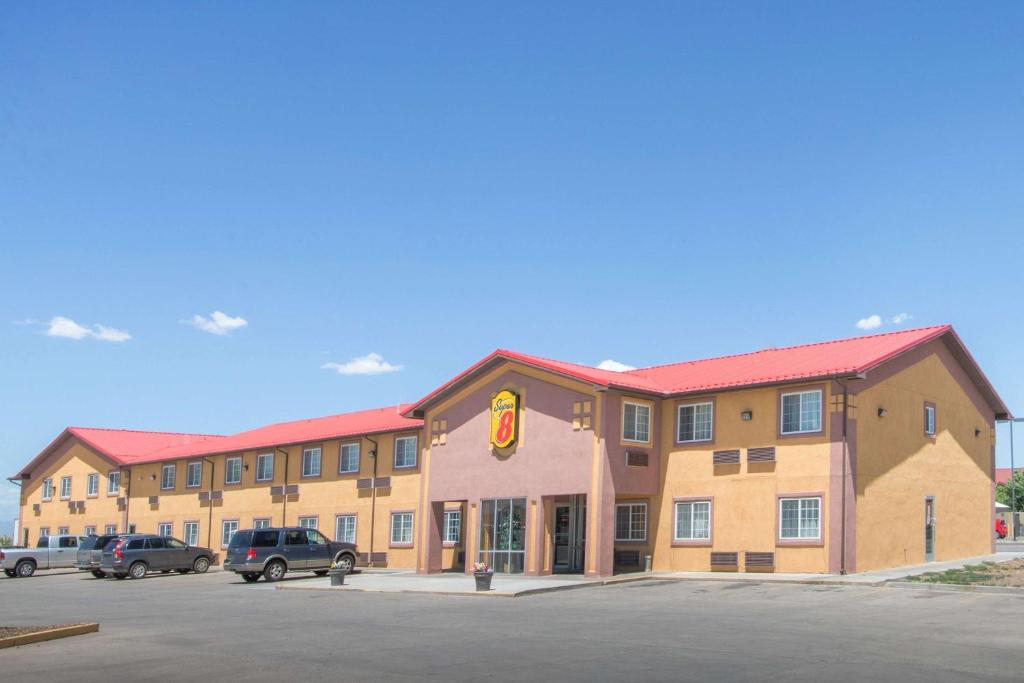 a large hotel with cars parked in a parking lot at Super 8 by Wyndham Moriarty in Moriarty