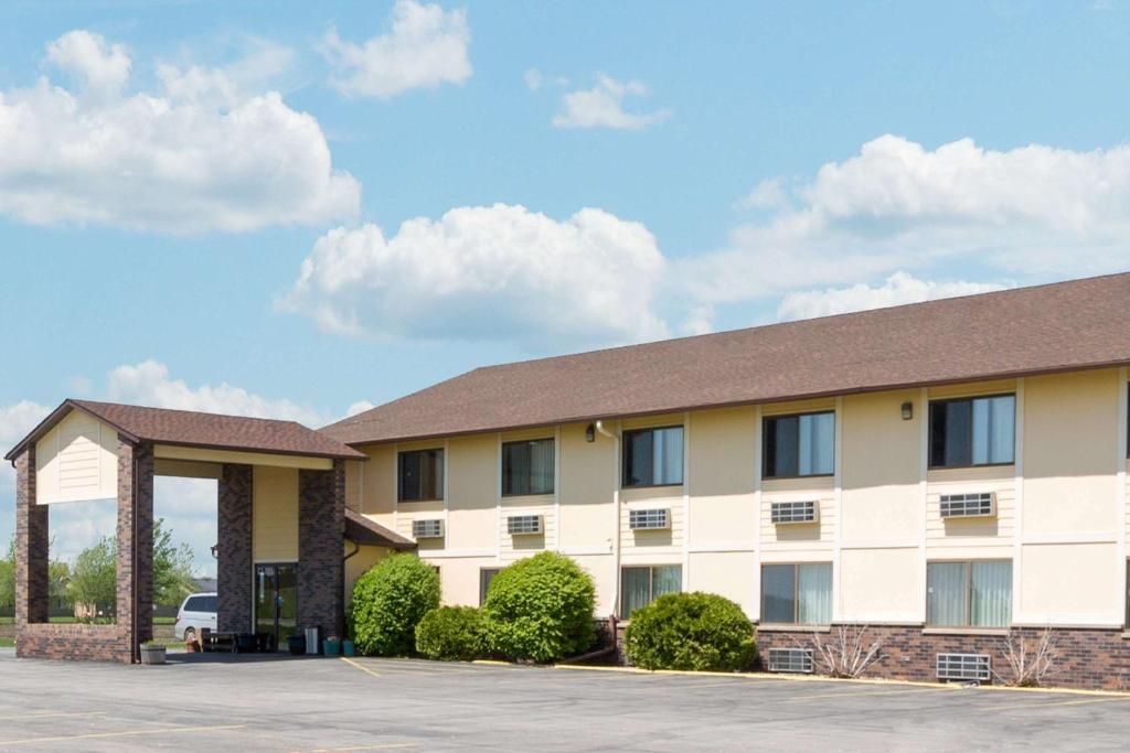 a large white building with a parking lot at Super 8 by Wyndham Perry IA in Perry