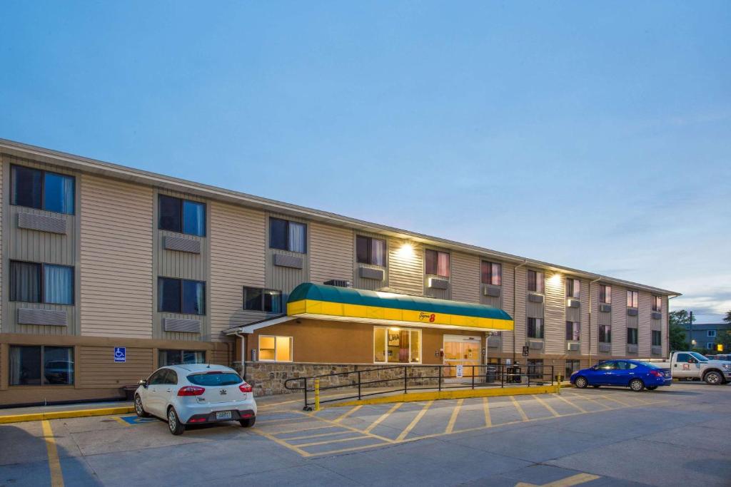 un gran edificio de apartamentos con coches aparcados en un aparcamiento en Super 8 by Wyndham Iowa City/Coralville, en Coralville