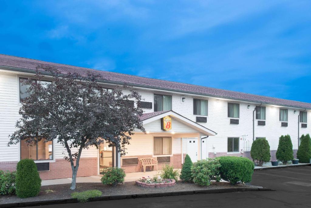 un bâtiment blanc avec un arbre devant lui dans l'établissement Super 8 by Wyndham Augusta, à Augusta