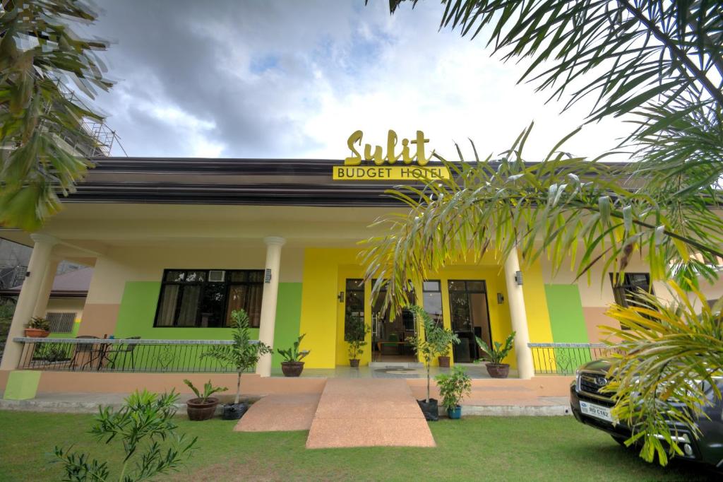 Sulit Budget Hotel near Dgte Airport Citimall في دوماغيتي: مبنى أصفر وأخضر مع وضع علامة عليه