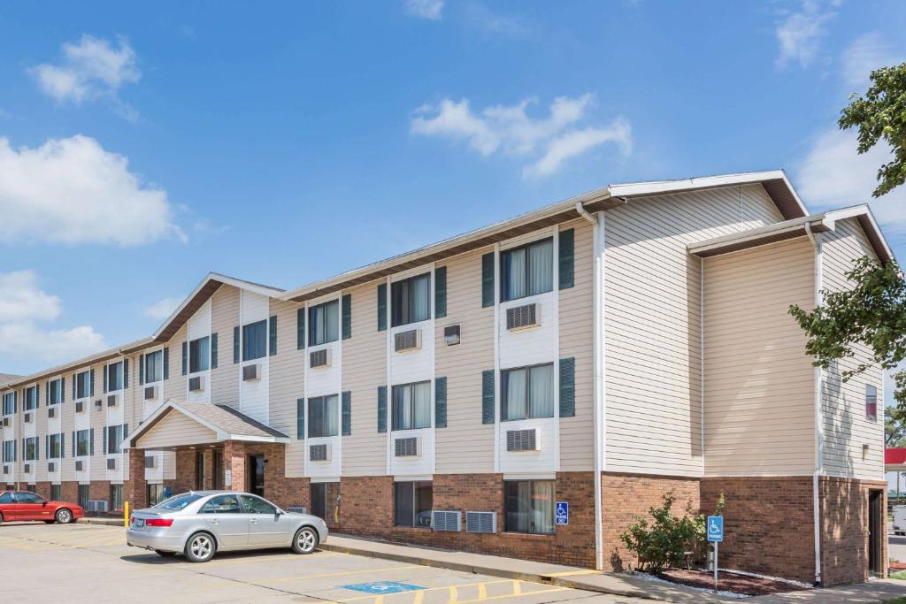 an apartment building with a car parked in a parking lot at Super 8 by Wyndham Manhattan KS in Manhattan