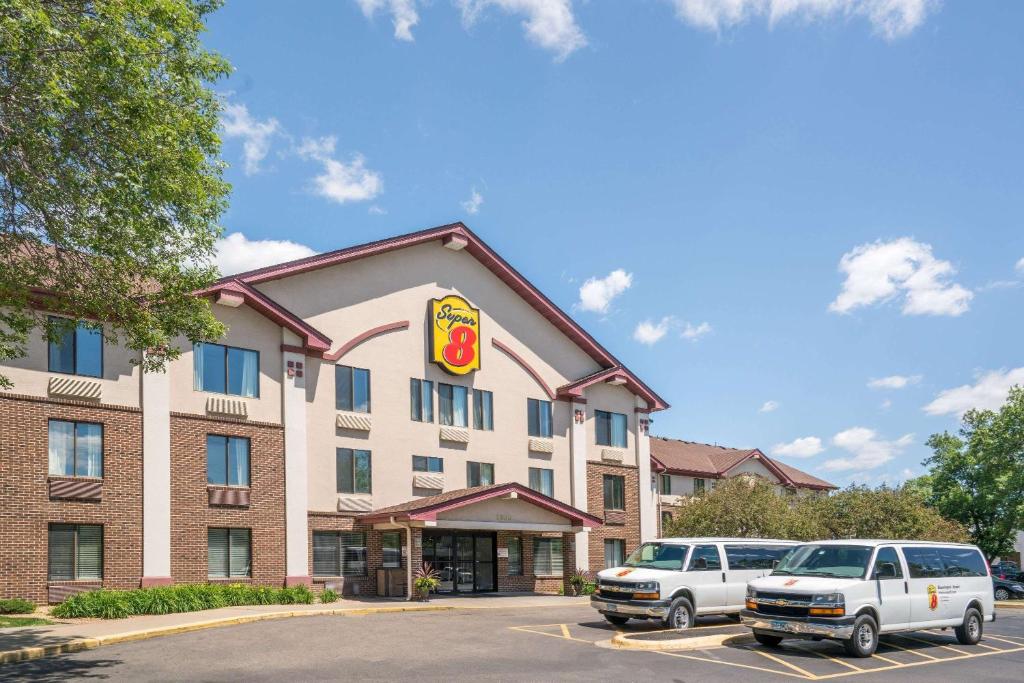 un hotel con dos coches estacionados frente a él en Super 8 by Wyndham Bloomington/Airport en Bloomington