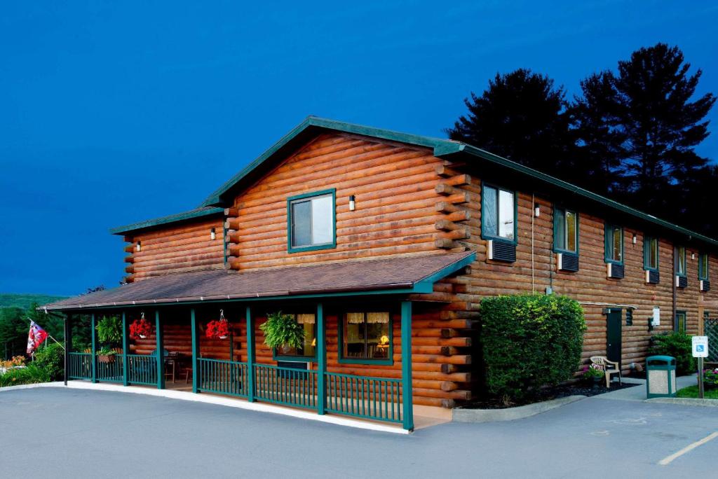 a log cabin with a parking lot in front of it at Super 8 by Wyndham Lake George/Warrensburg Area in Warrensburg