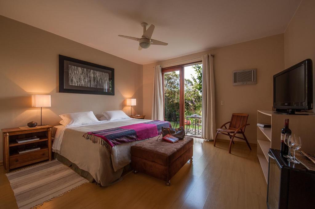 a bedroom with a bed and a flat screen tv at Pousada Maya in Alto Paraíso de Goiás