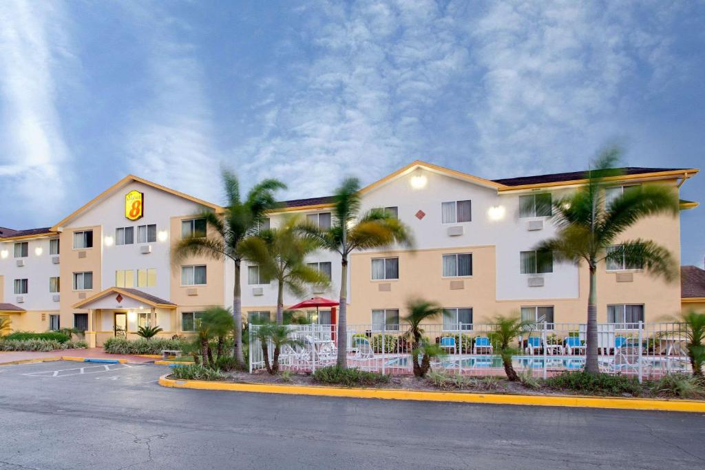 a hotel with palm trees in front of a building at Super 8 by Wyndham Clearwater/St. Petersburg Airport in Clearwater
