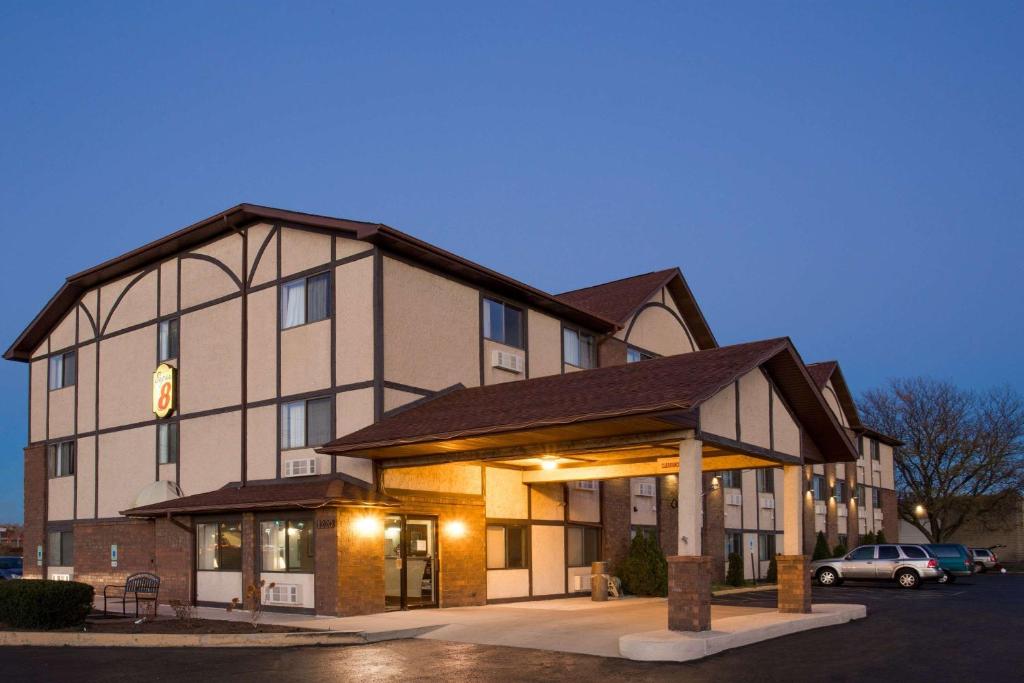 a large building with a car parked in a parking lot at Super 8 by Wyndham Woodstock in Woodstock