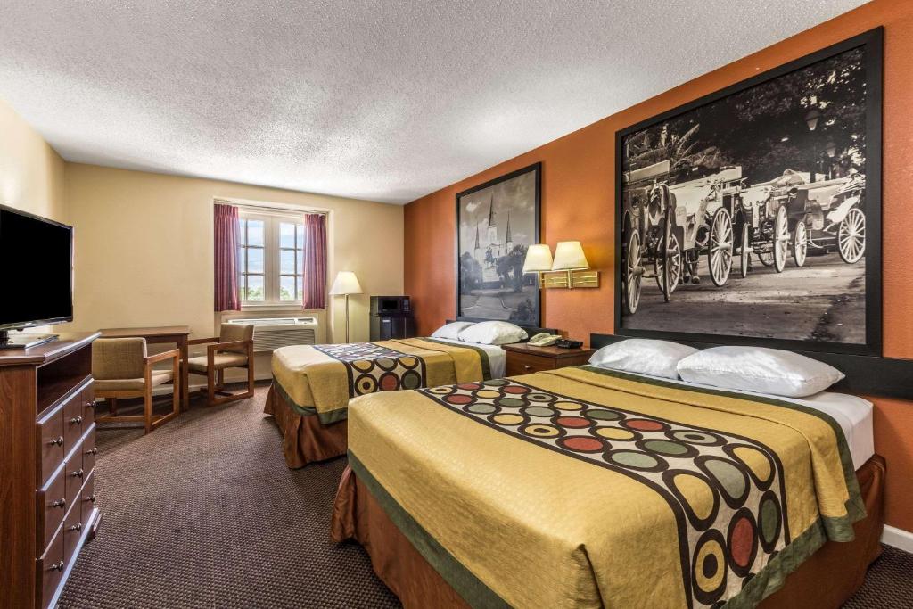 a hotel room with two beds and a flat screen tv at Super 8 by Wyndham New Orleans in New Orleans