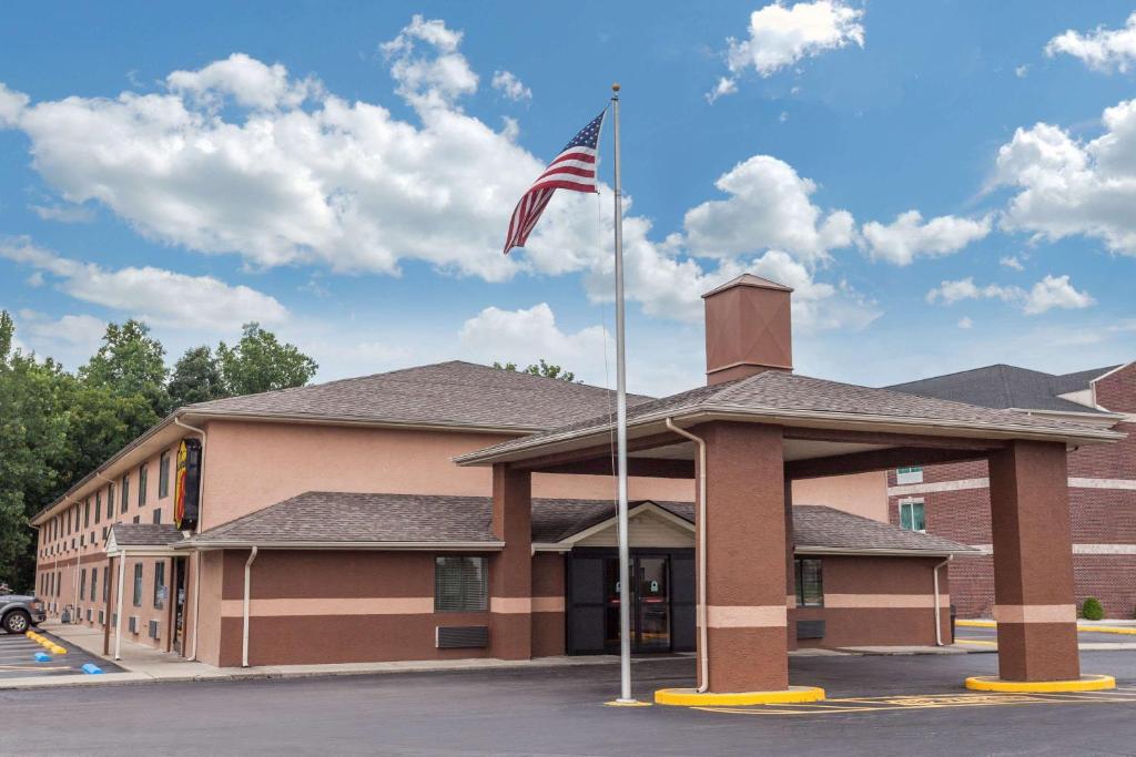 a building with an american flag in front of it at Super 8 by Wyndham Carrollton in Carrollton