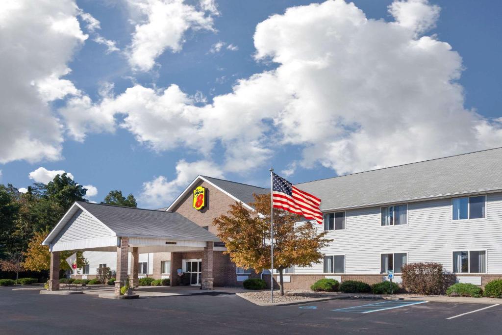 a hotel with an american flag in front of it at Super 8 by Wyndham Adrian in Adrian