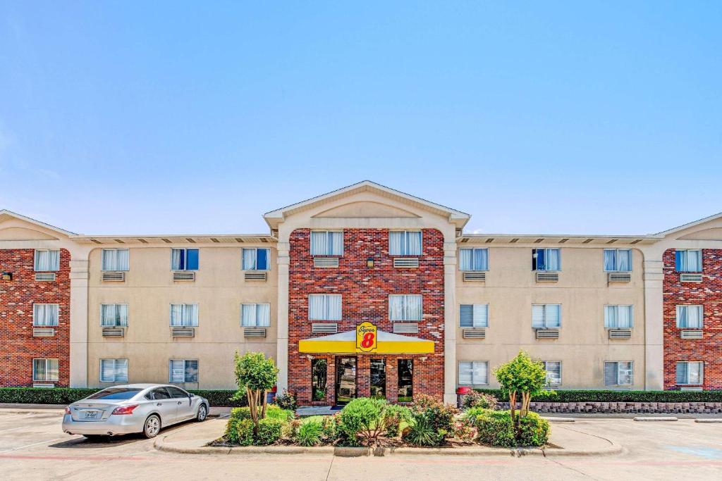 a large brick building with a restaurant sign in a parking lot at Super 8 by Wyndham McKinney/Plano Area in McKinney