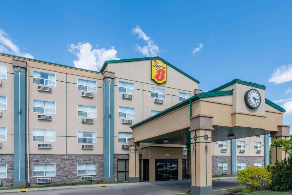 a hotel with a clock on the front of it at Super 8 by Wyndham Red Deer City Centre in Red Deer