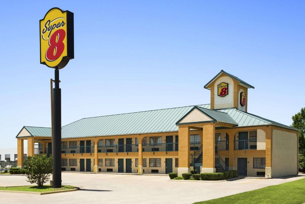 ein großes Gebäude mit einem Fastfood-Schild davor in der Unterkunft Super 8 by Wyndham Grand Prairie Southwest in Grand Prairie