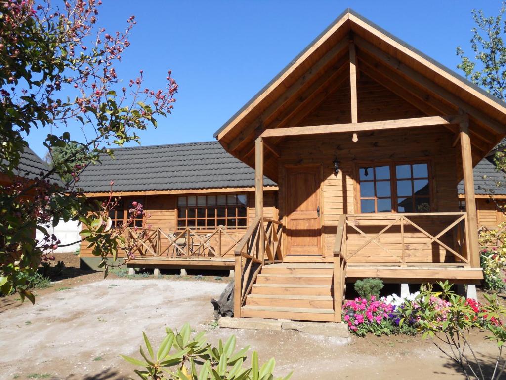 uma cabana de madeira com um alpendre e uma casa em L'Emiliano Cabañas-Ristorante em Capitán Pastene