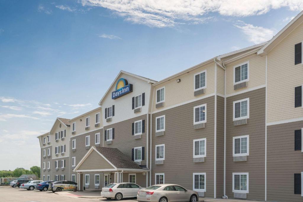 a hotel with cars parked in a parking lot at Days Inn & Suites by Wyndham Rochester South in Rochester