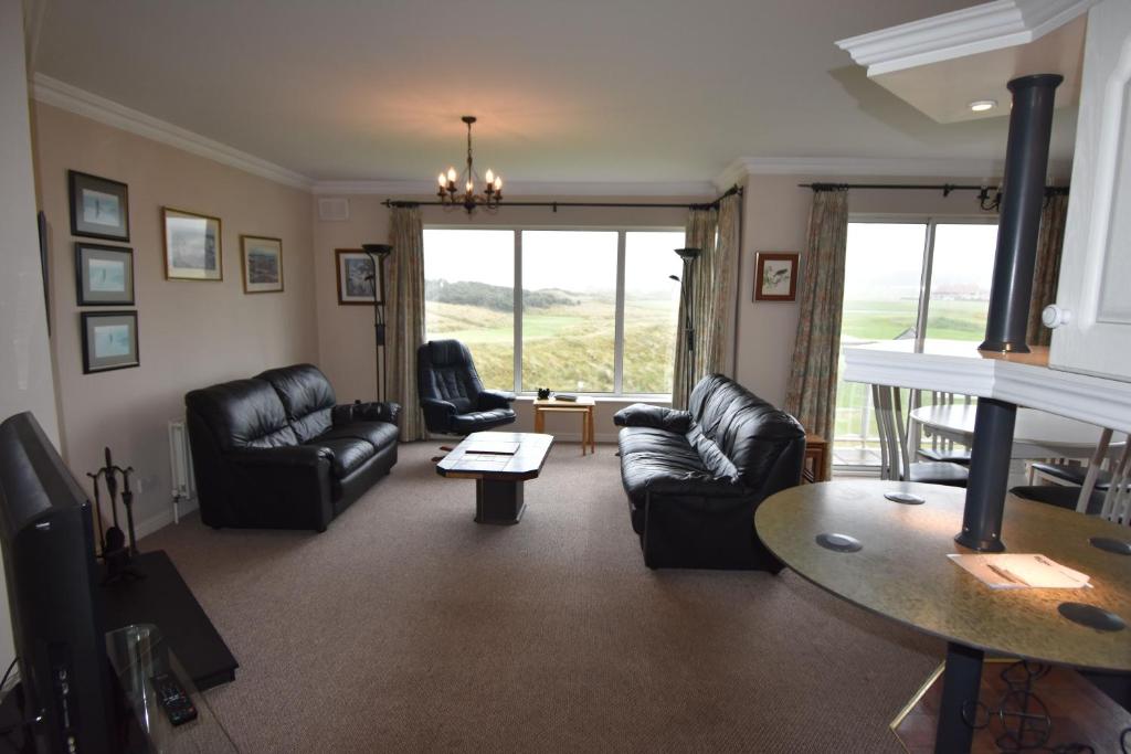 a living room with black leather furniture and a table at The Links Apartment Portrush in Portrush