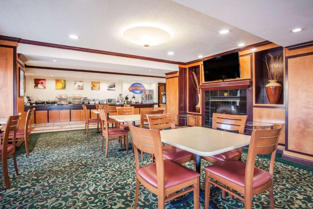 a restaurant with tables and chairs and a bar at Baymont by Wyndham Madison Heights Detroit Area in Madison Heights