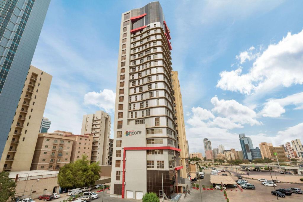 a tall building in the middle of a city at Ramada Encore by Wyndham Kuwait Downtown in Kuwait