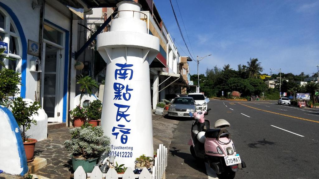 a scooter parked next to a building with writing on a pole at Nandian Homestay in Eluan