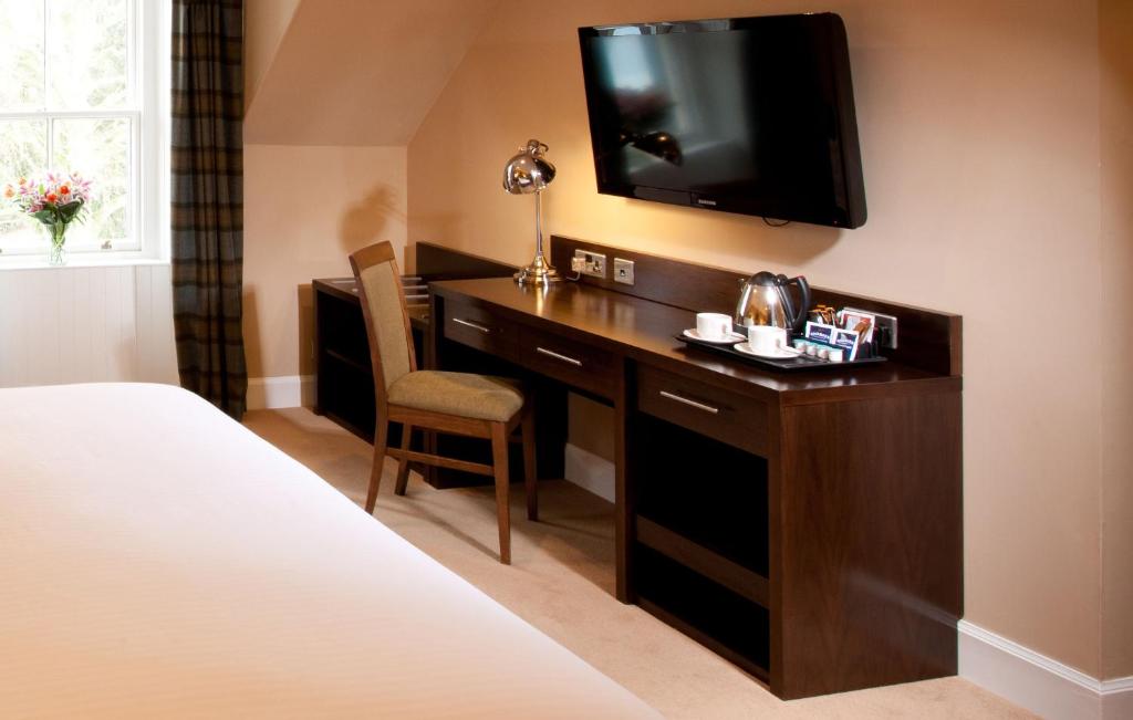 a hotel room with a desk with a television on a wall at Leonardo Boutique Huntingtower Perth in Perth