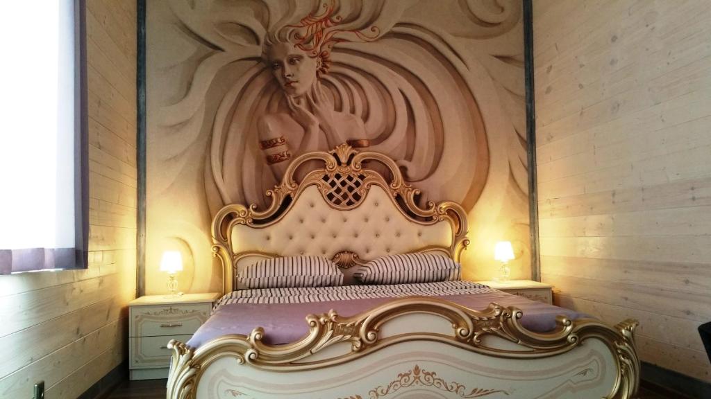 マイコープにあるГостиница Майкоп Ситиのベッドルーム1室(壁に絵画が描かれた金のベッド1台付)