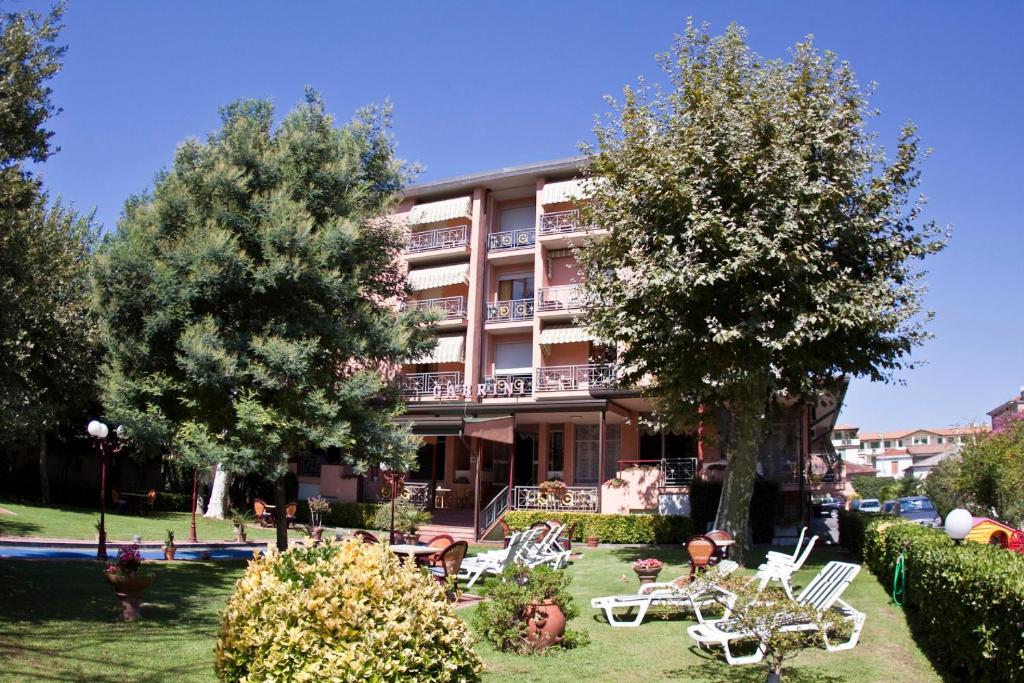 un hotel con mesas y sillas en un patio en Hotel Gabrini en Marina di Massa