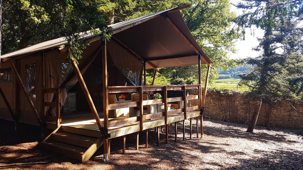 a tent with a porch with trees in the background at Le Lodge du Domaine Saint Martin in Flassans-sur-Issole