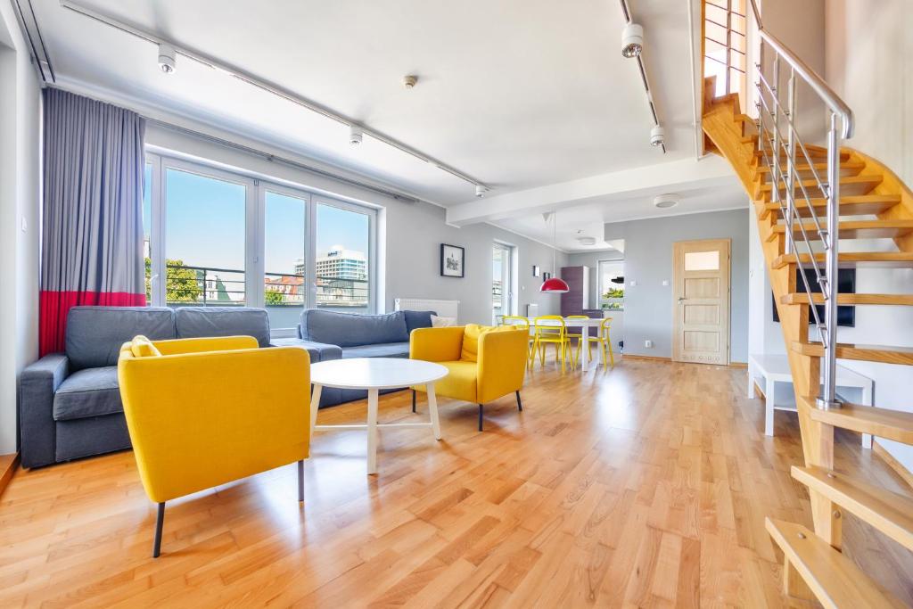ein Wohnzimmer mit einem Sofa, einem Tisch und gelben Stühlen in der Unterkunft Apartamenty Sun & Snow Casa Marina in Świnoujście