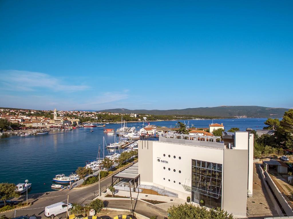 ein großes weißes Gebäude neben einem Wasserkörper in der Unterkunft Hotel Maritime in Krk