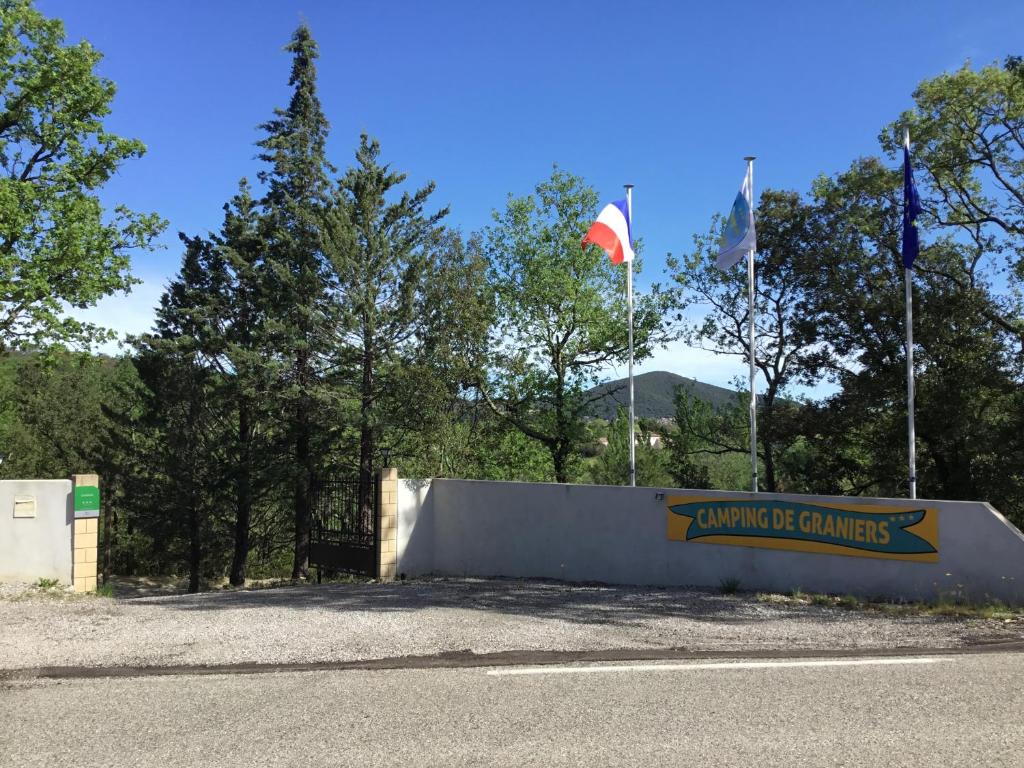 a sign for the entrance to the winning campgrounds with two flags at Camping de Graniers in Monoblet