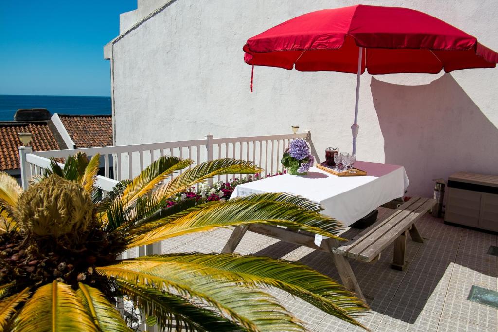 サン・ロケにあるPopulo Beach Houseの海の見えるバルコニーにテーブルと赤い傘