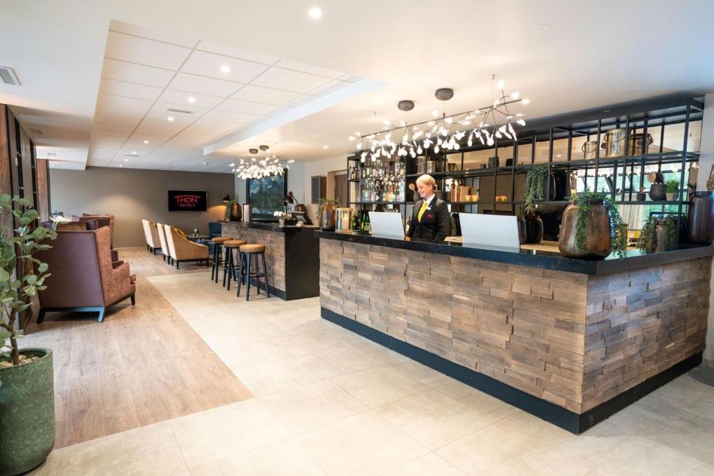 a woman standing at a bar in a restaurant at Thon PartnerHotel Førde in Førde