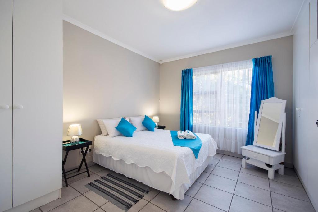 1 dormitorio con 1 cama y una ventana con cortinas azules en 2 on Bashee, en Port Elizabeth