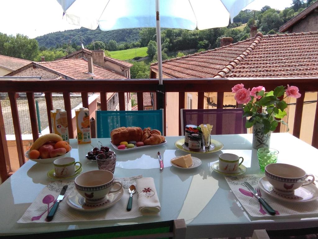 una mesa con tazas y platos de comida en el balcón en Chambre d'hôtes Les Myriades D'Or, en Regny