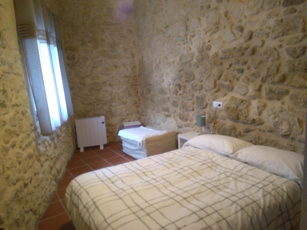 a bedroom with two beds and a stone wall at Casa Rural La Tia Rosa in Chulilla