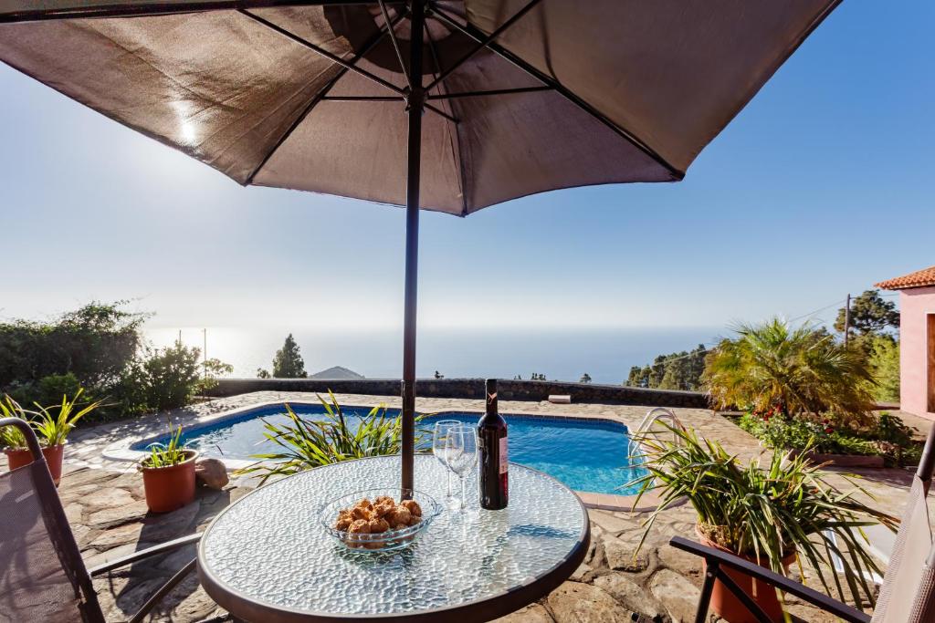 a table with an umbrella next to a swimming pool at La Verada in Puntagorda