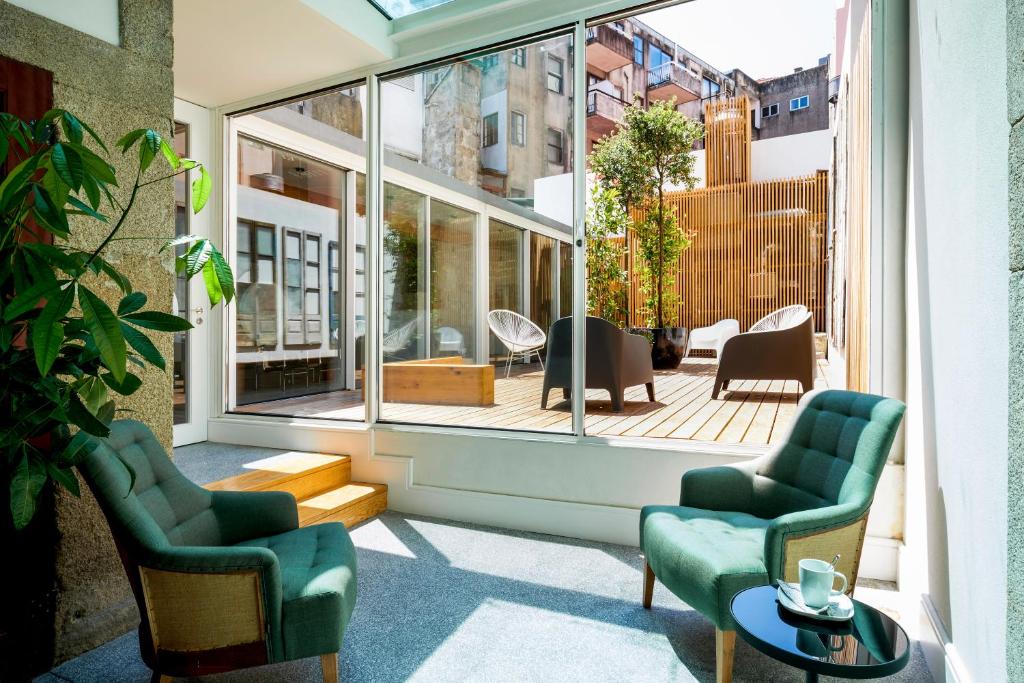 a patio with two chairs and a table and a large window at The A5 Smart Luxury Studios in Porto