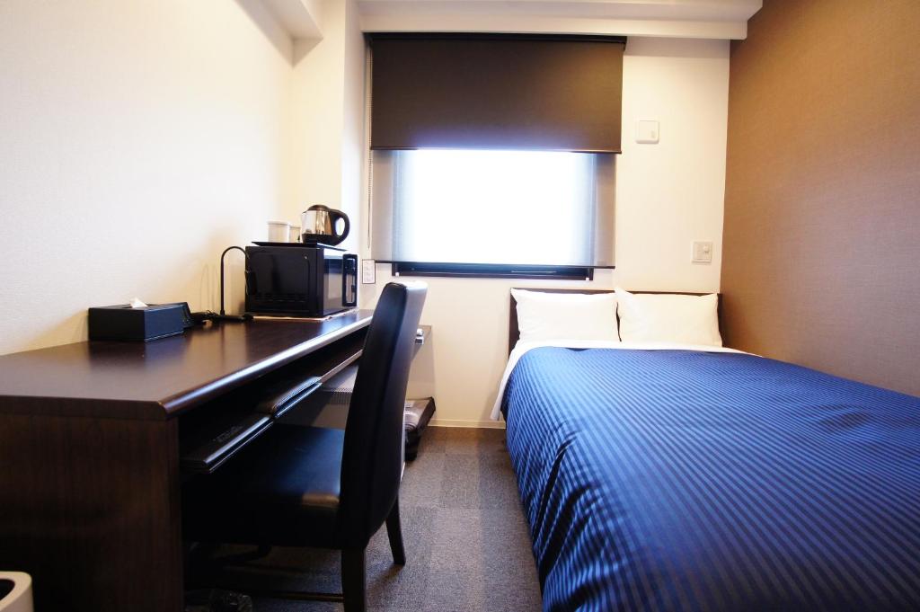 Postel nebo postele na pokoji v ubytování HOTEL LiVEMAX Kanazawa Ekimae