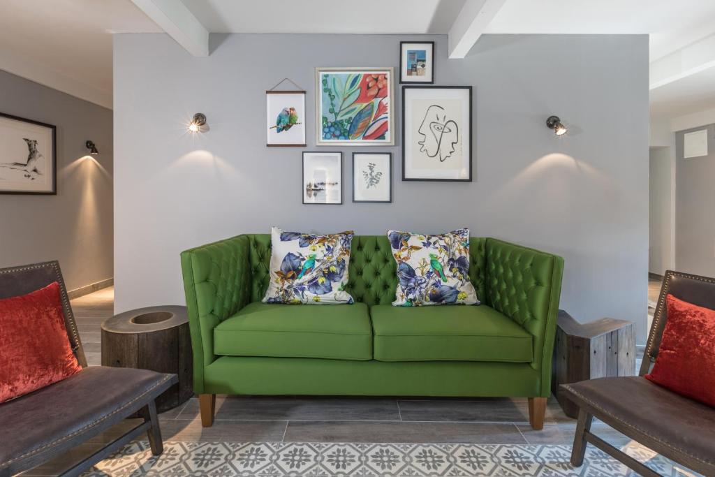 a green couch in a living room with two chairs at Mas du Brulat in Le Castellet