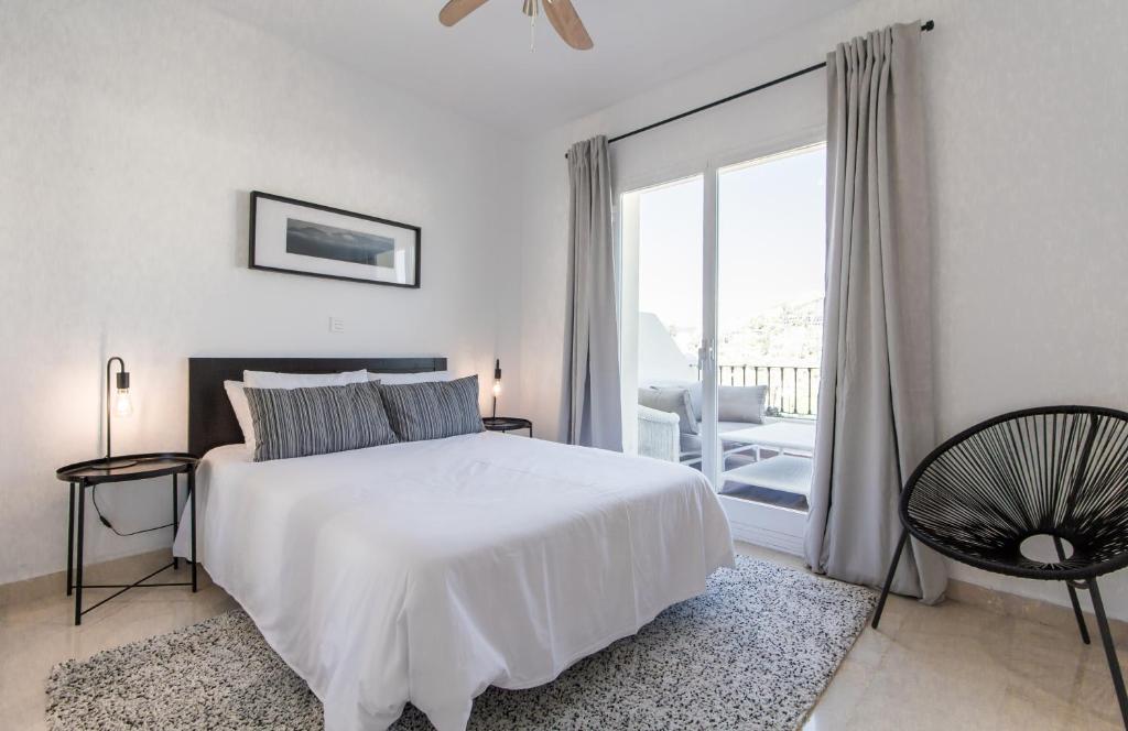 biała sypialnia z łóżkiem i dużym oknem w obiekcie Jacuzzi Rooftop Bbq Wifi Pool Music Netflix Games w mieście Benahavís