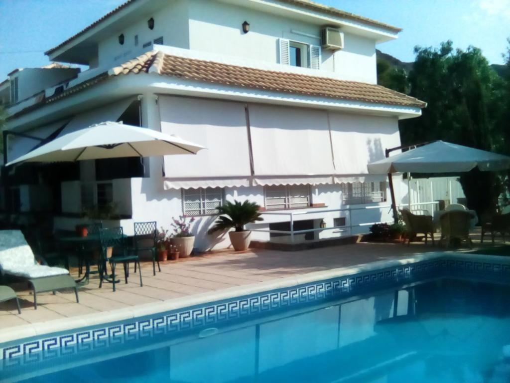 a villa with a swimming pool in front of a house at Chalet con dos apartamentos in La Azohía
