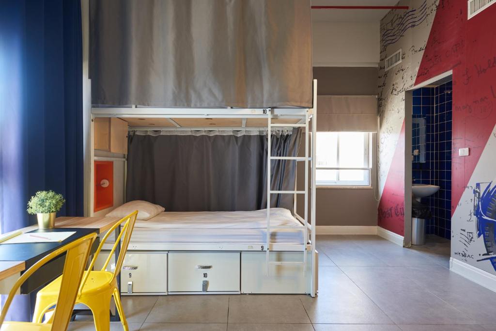 a room with a bunk bed with a desk and a table at The Post Hostel Jerusalem in Jerusalem
