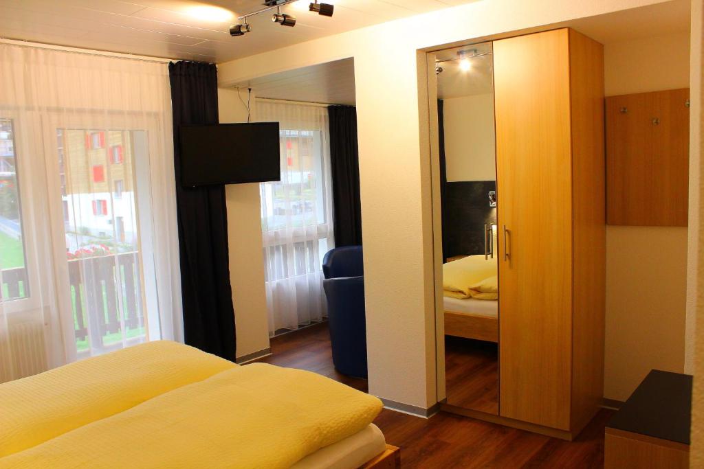 a room with a bedroom with a mirror and a bed at Hotel Alpha in Grächen
