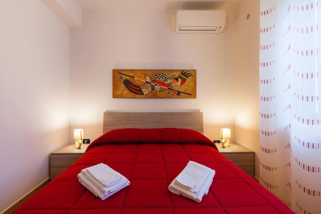 una camera con un letto rosso e due asciugamani bianchi di Sweet Home La Ville a Caserta