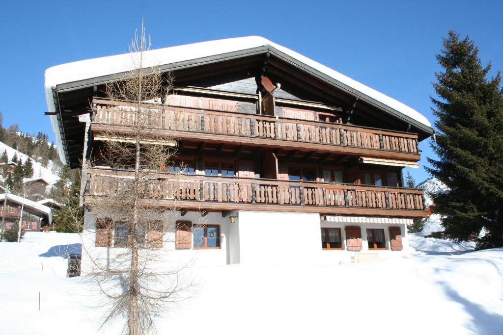 een houten gebouw met een balkon in de sneeuw bij Gamma in Blatten bei Naters