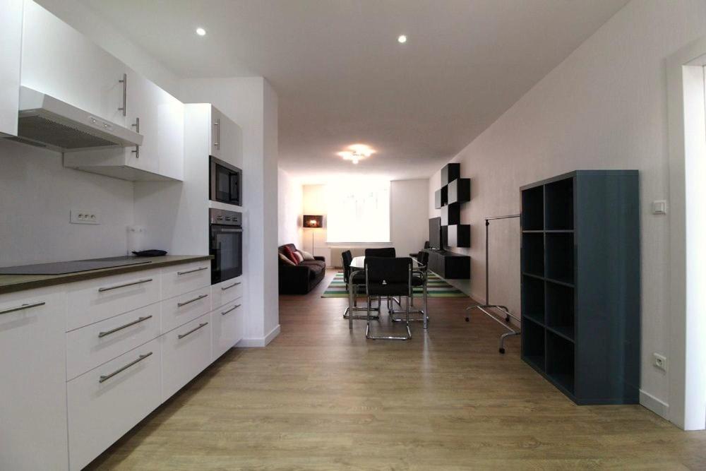 a kitchen with white cabinets and a dining room at Appartements Le Cru Colbert in Beaune