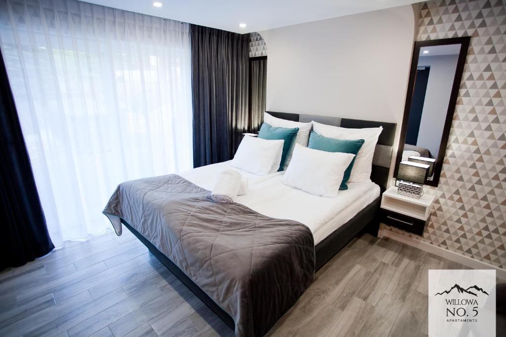 1 dormitorio con 1 cama grande con almohadas azules y blancas en Willowa NO. 5 APARTAMENTS, en Wisła