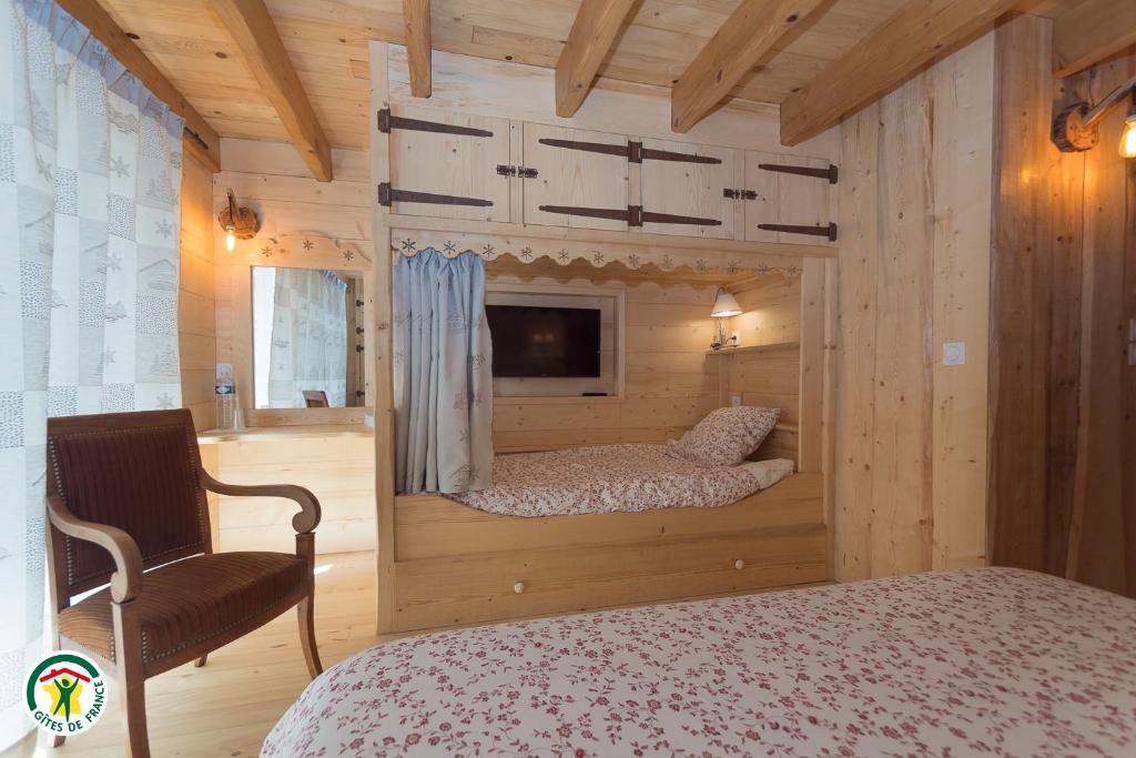 Saint-LattierにあるChalet le Clos de l'Ormeのベッドルーム(ベッド1台、テレビ、椅子付)