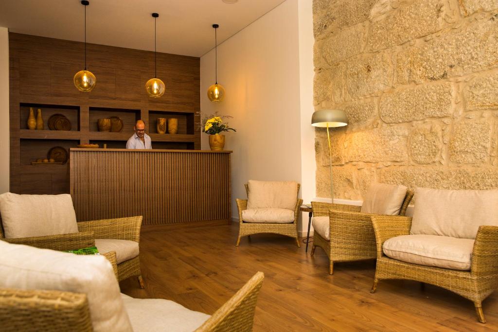 a man standing in a lobby with chairs and a bar at BO - Álvares Cabral GuestHouse in Porto