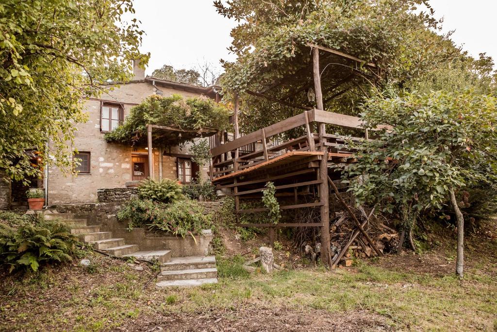 a house with a deck and stairs in front of it at Melia Cottage in Tsagarada